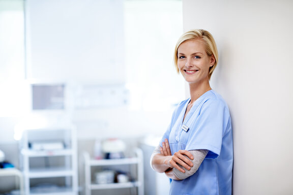 Mitarbeiterin in der Pflege schaut zufrieden in die Kamera